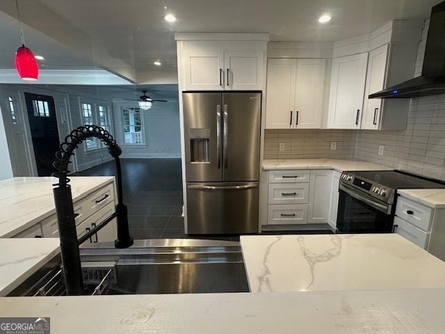 kitchen with wall chimney exhaust hood, white cabinetry, tasteful backsplash, decorative light fixtures, and stainless steel appliances