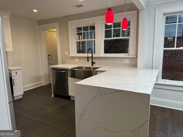 kitchen with sink, dishwasher, hanging light fixtures, light stone countertops, and white cabinets