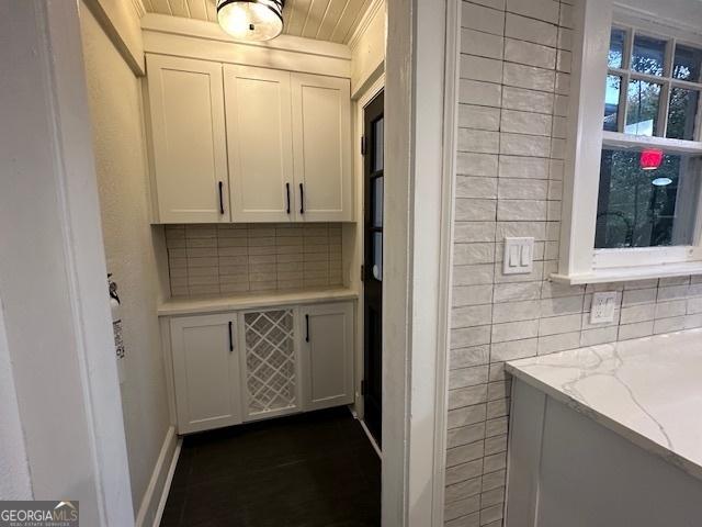 interior space with white cabinetry, wooden ceiling, light stone counters, and decorative backsplash