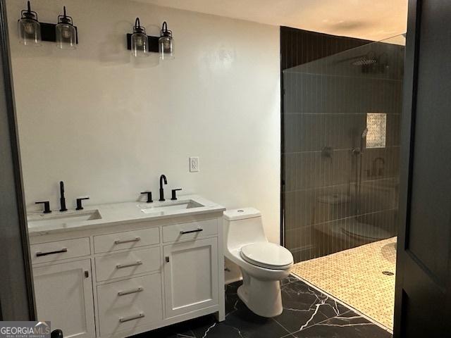 bathroom with vanity, tiled shower, and toilet