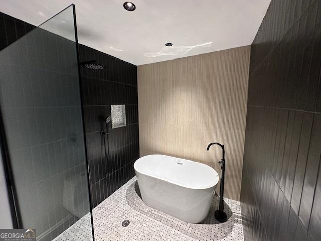 bathroom featuring independent shower and bath and tile walls