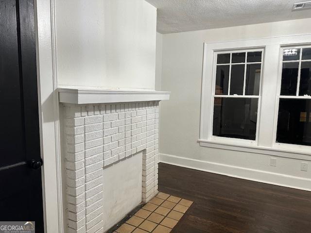 details featuring a brick fireplace, hardwood / wood-style floors, and a textured ceiling