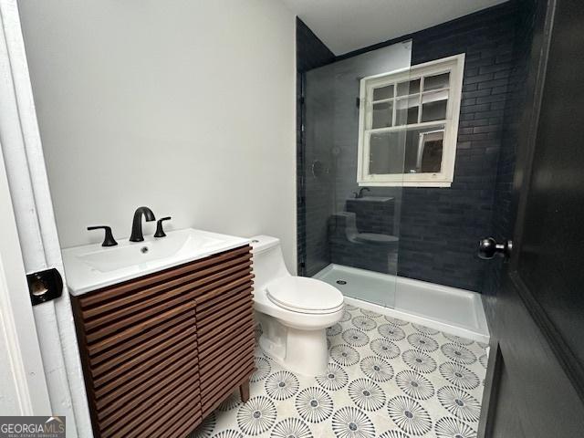 bathroom featuring vanity, toilet, and tiled shower