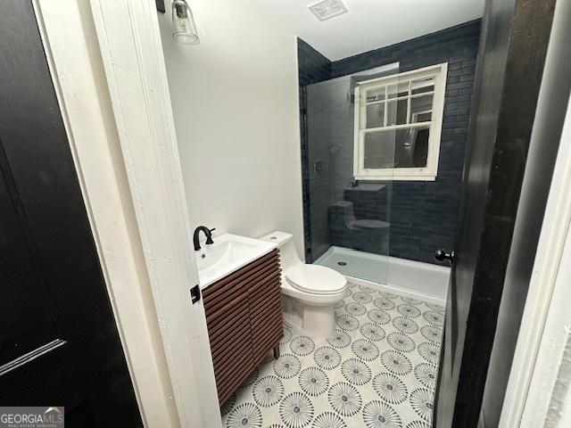 bathroom with vanity, a shower with door, and toilet