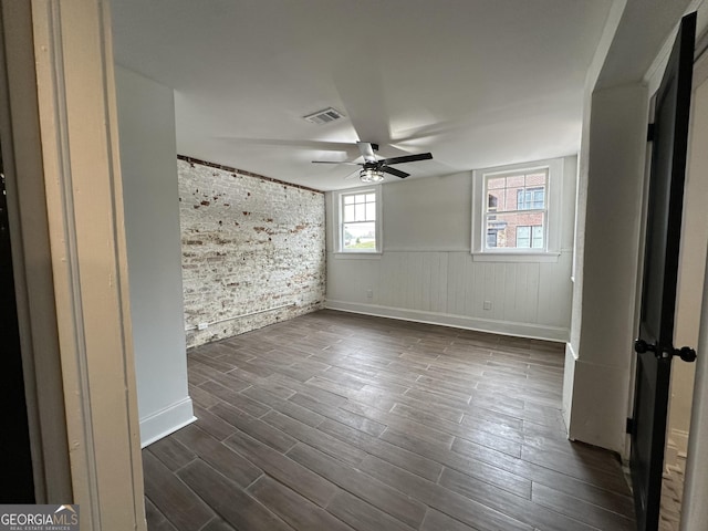 unfurnished room featuring ceiling fan, brick wall, and dark hardwood / wood-style flooring