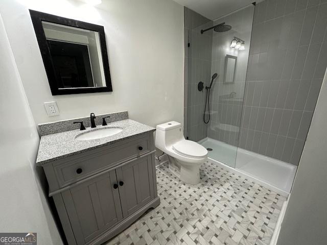 bathroom featuring vanity, toilet, and tiled shower