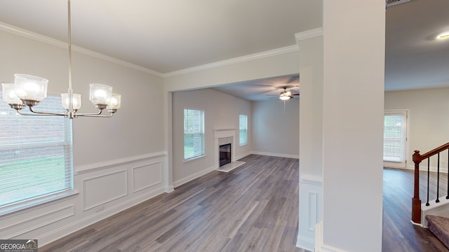 unfurnished living room with ceiling fan with notable chandelier, crown molding, and dark wood-type flooring