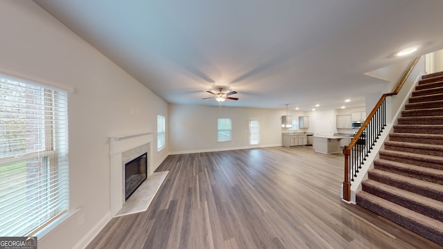 unfurnished living room with ceiling fan, wood-type flooring, and a premium fireplace