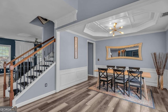 dining area with ceiling fan with notable chandelier, wood-type flooring, crown molding, and coffered ceiling