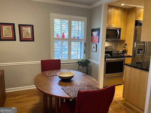 dining area with ornamental molding and light wood-type flooring