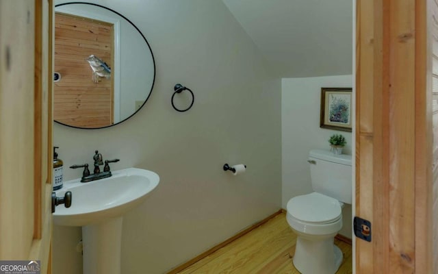 bathroom featuring toilet, hardwood / wood-style floors, vaulted ceiling, and sink