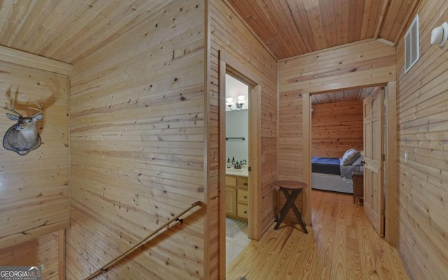 hall with wooden walls, light hardwood / wood-style flooring, and wooden ceiling