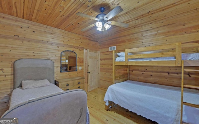 bedroom featuring light wood-type flooring, wood ceiling, ceiling fan, and wood walls