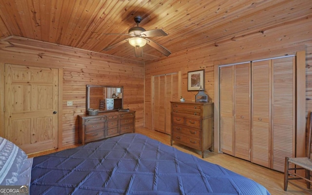 bedroom with ceiling fan, wooden walls, wooden ceiling, hardwood / wood-style floors, and multiple closets