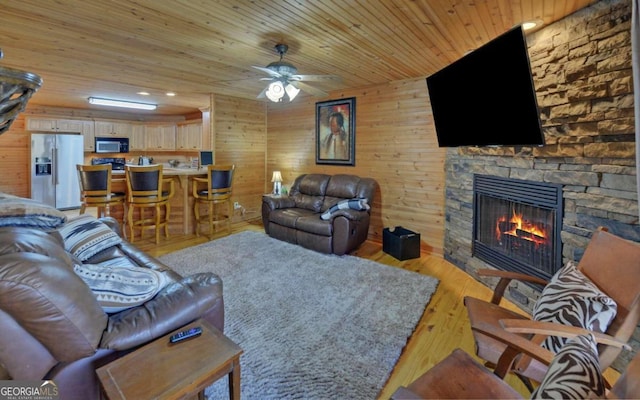 living room with a fireplace, light hardwood / wood-style flooring, wooden walls, and wood ceiling