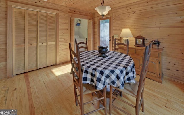 dining room with wood walls and light hardwood / wood-style flooring