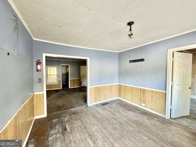 empty room featuring dark hardwood / wood-style floors, ornamental molding, and wooden walls