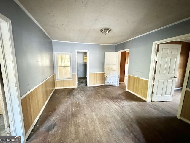 unfurnished bedroom featuring dark hardwood / wood-style floors, wood walls, and crown molding