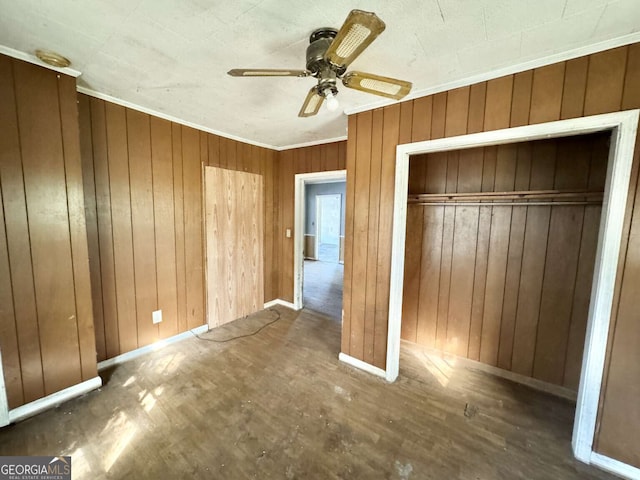 unfurnished bedroom featuring ceiling fan, wood walls, dark hardwood / wood-style floors, and a closet