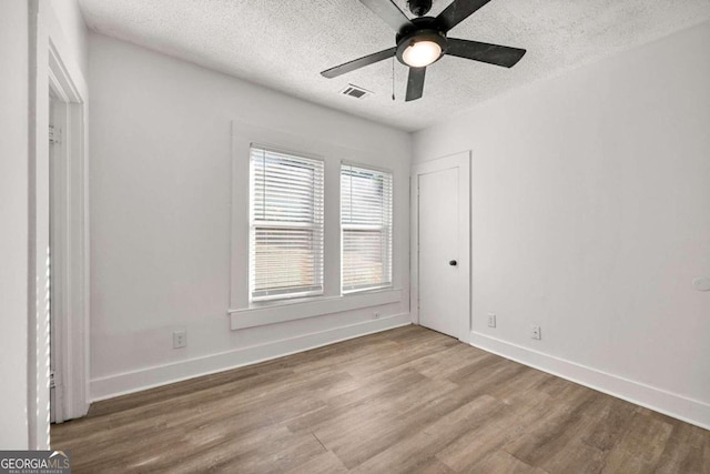 unfurnished bedroom featuring hardwood / wood-style floors, ceiling fan, and a textured ceiling