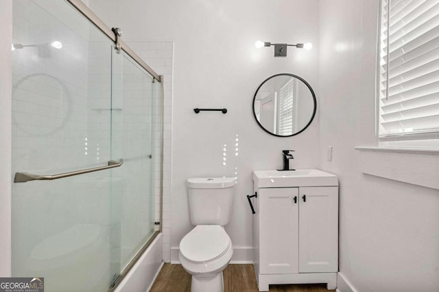 full bathroom with hardwood / wood-style floors, vanity, toilet, and bath / shower combo with glass door