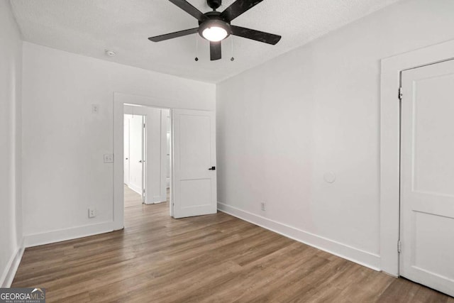 empty room with ceiling fan, a textured ceiling, and hardwood / wood-style flooring