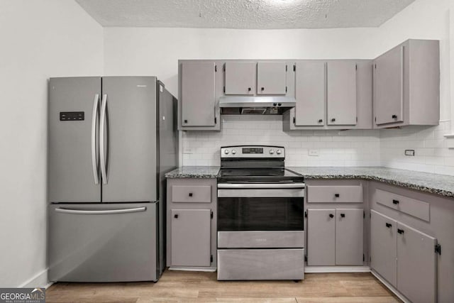 kitchen with stainless steel appliances, gray cabinets, tasteful backsplash, and light hardwood / wood-style floors