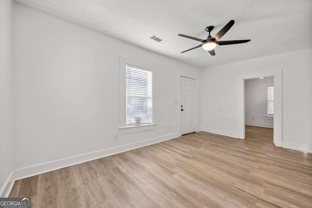 spare room with ceiling fan, light hardwood / wood-style flooring, and a textured ceiling