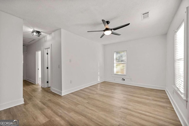 unfurnished room featuring ceiling fan, light wood-type flooring, and a textured ceiling