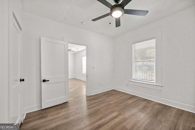 empty room with hardwood / wood-style flooring, ceiling fan, and a textured ceiling