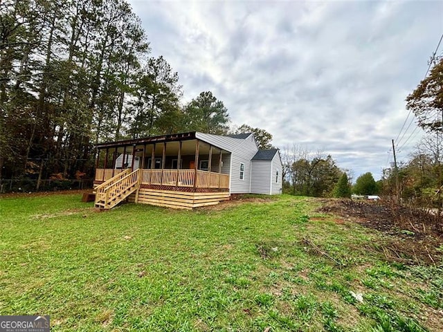 rear view of house with a deck and a yard