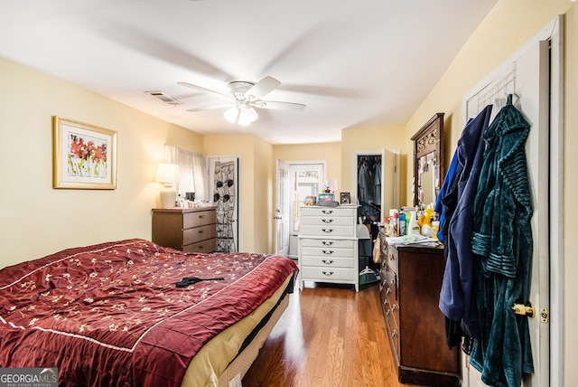 bedroom with ceiling fan, a closet, a spacious closet, and hardwood / wood-style flooring