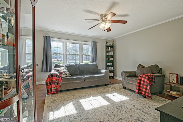 living room with hardwood / wood-style flooring, ceiling fan, ornamental molding, and a textured ceiling