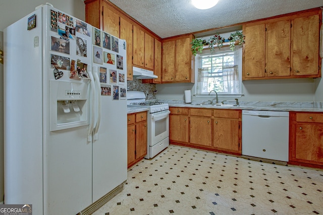 kitchen featuring a textured ceiling, white appliances, and sink