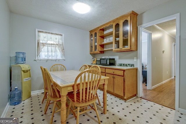 dining area with ornamental molding, a textured ceiling, and light hardwood / wood-style flooring