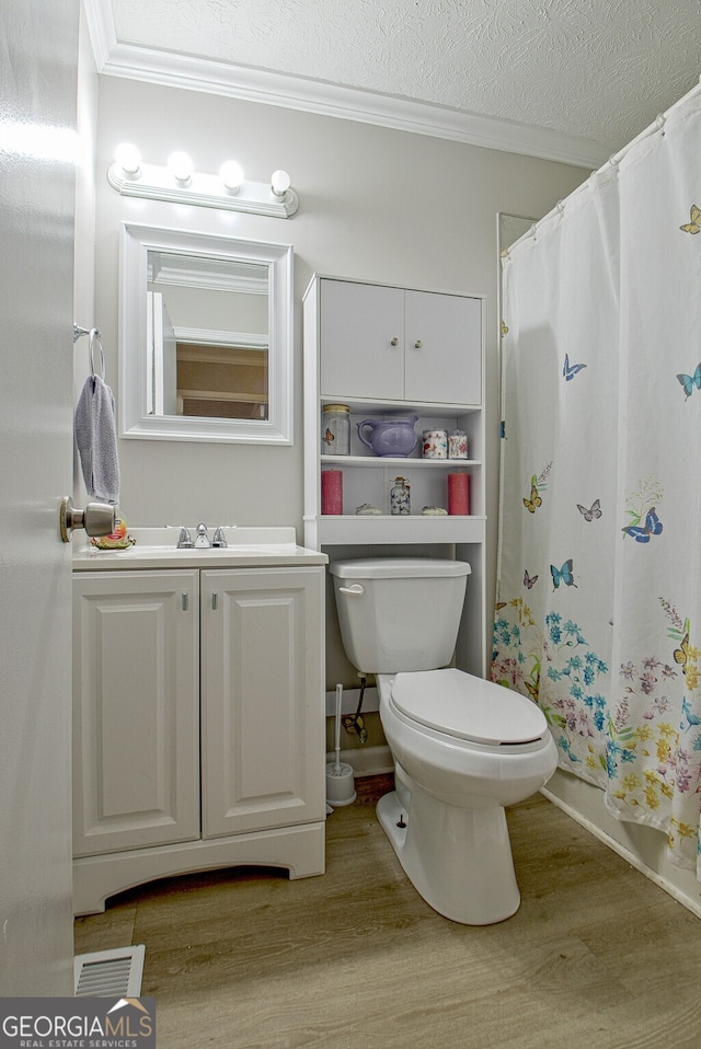 full bathroom featuring hardwood / wood-style floors, a textured ceiling, toilet, and crown molding