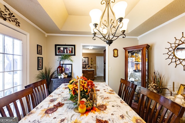 dining area with a raised ceiling, crown molding, a textured ceiling, and a notable chandelier