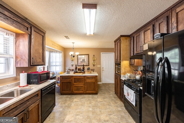 kitchen featuring a textured ceiling, sink, black appliances, a chandelier, and hanging light fixtures