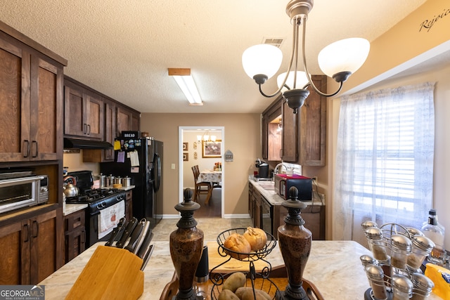 kitchen featuring black appliances, dark brown cabinetry, hanging light fixtures, and a chandelier