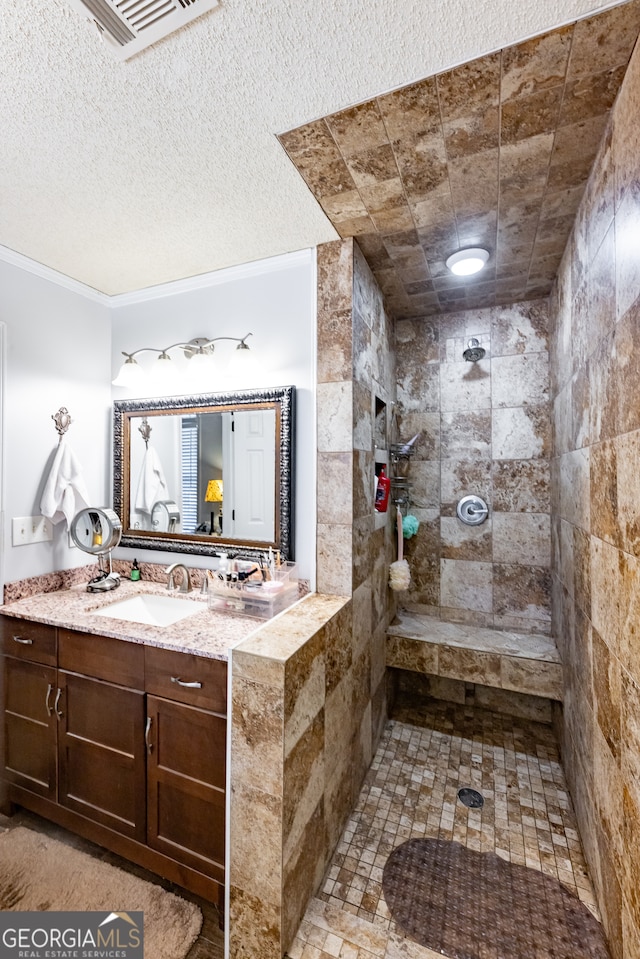 bathroom with a tile shower, vanity, a textured ceiling, and crown molding