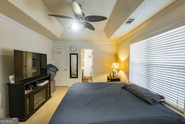 bedroom featuring ceiling fan, crown molding, a textured ceiling, a tray ceiling, and light carpet