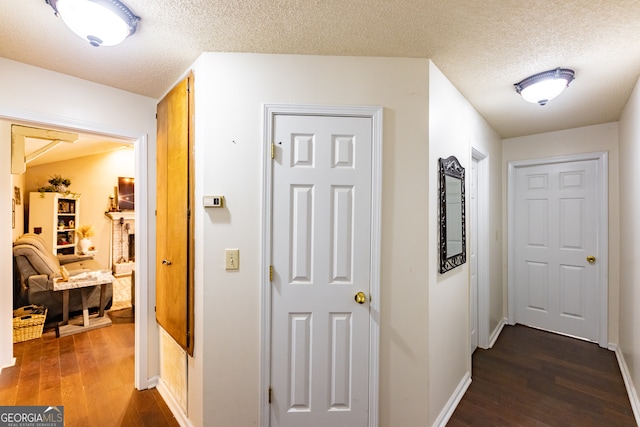 corridor with a textured ceiling and dark wood-type flooring