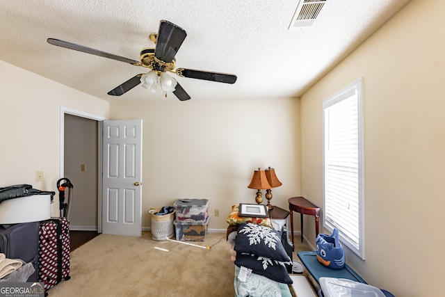 interior space featuring a textured ceiling, ceiling fan, and light carpet