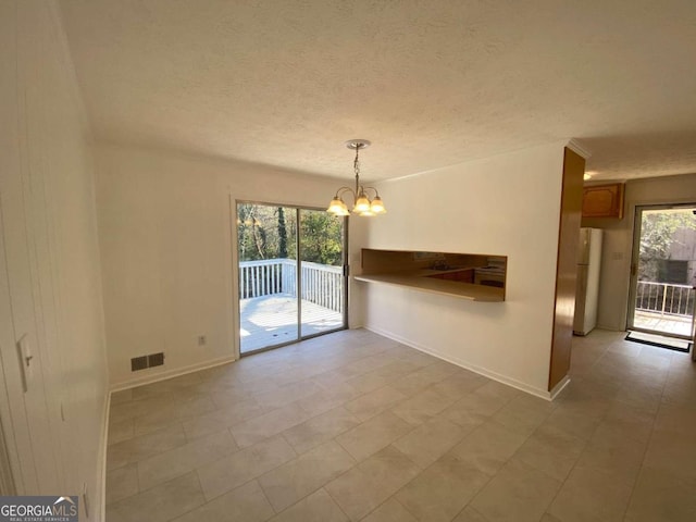 tiled empty room with a textured ceiling and a chandelier