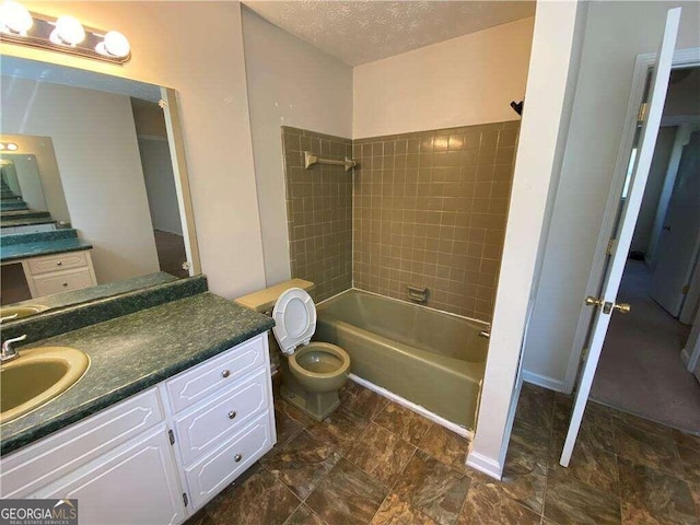 full bathroom featuring a textured ceiling, vanity, toilet, and tiled shower / bath