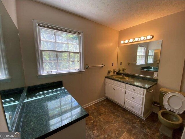 bathroom with vanity, toilet, and a textured ceiling