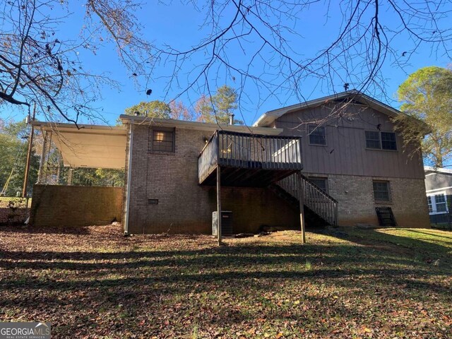 back of property with a lawn and a wooden deck