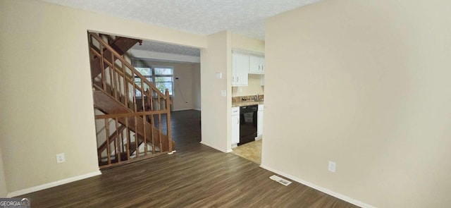 spare room featuring a textured ceiling and dark hardwood / wood-style floors