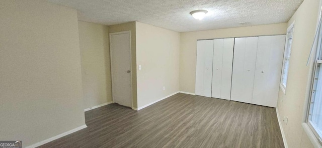 unfurnished bedroom with a textured ceiling, a closet, and dark hardwood / wood-style floors