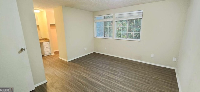 spare room with a textured ceiling and dark hardwood / wood-style floors